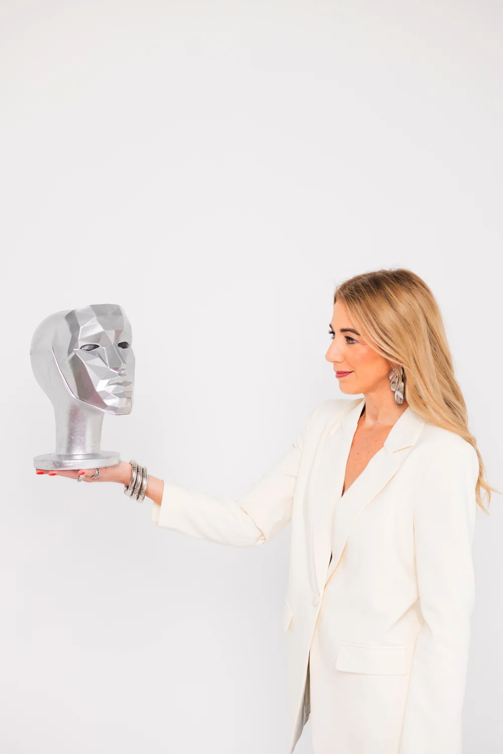 Heather Nianouris holding a metallic face sculpture
